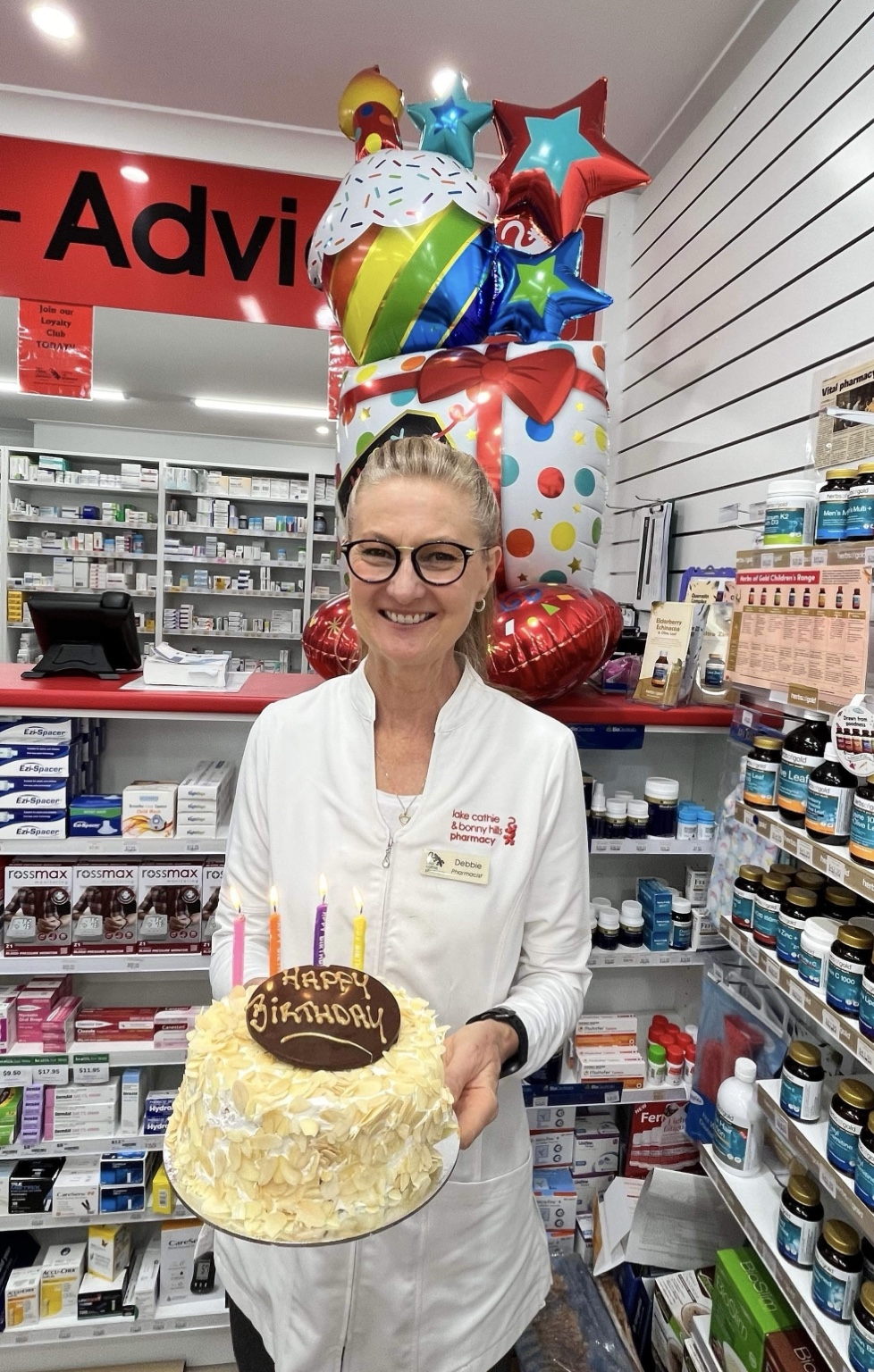 A pharmacy team member holding a birthday cake