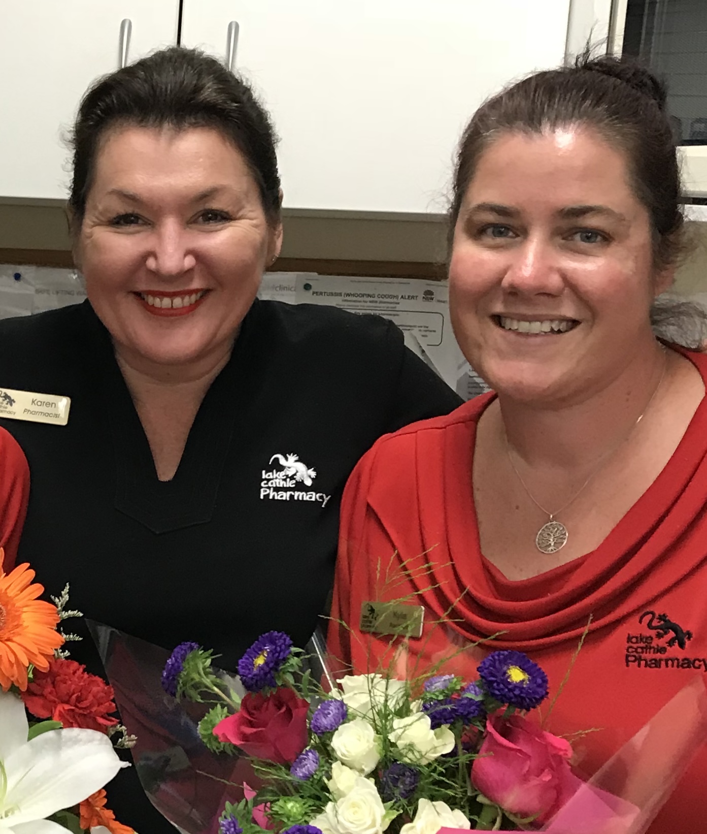 Two pharmacy team members with bouquets of flowers